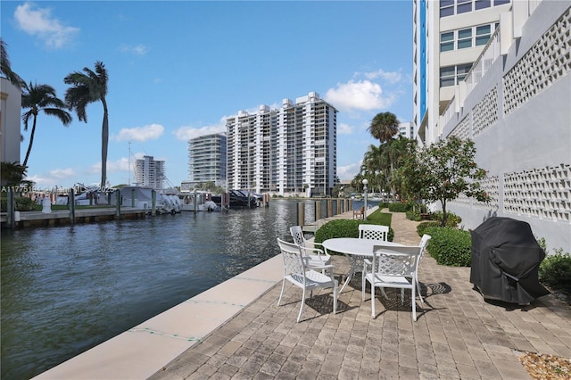 view of patio / terrace with grilling area, a water view, and outdoor dining area