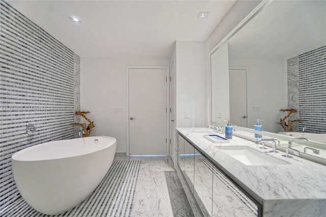 788 NE 23rd St Unit 1001, Miami, FL 33137 - bathroom featuring double vanity, an accent wall, a soaking tub, marble finish flooring, and tile walls