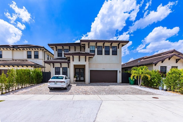 view of front facade featuring a garage, stucco siding, and decorative driveway
