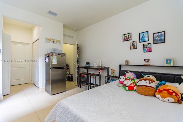 bedroom with visible vents, freestanding refrigerator, and light tile patterned flooring