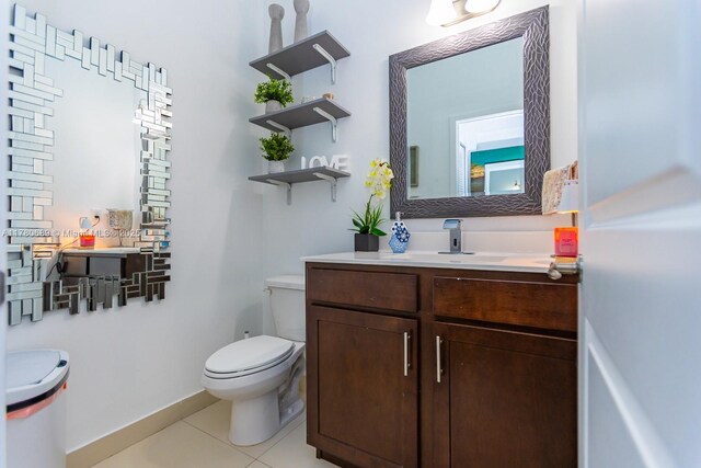 bathroom with toilet, vanity, and tile patterned flooring