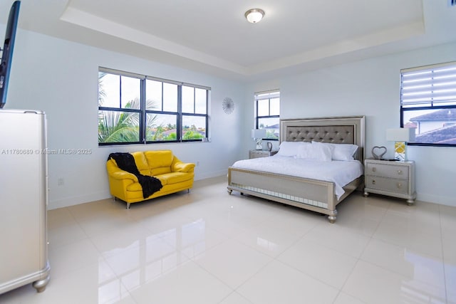 tiled bedroom featuring a tray ceiling and baseboards