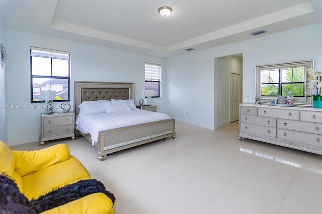 bedroom featuring visible vents, baseboards, and a raised ceiling