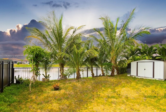 view of yard with a fenced backyard, an outdoor structure, and a storage unit