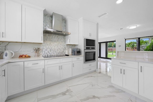 1951 NE 187th Dr, North Miami Beach, FL 33179 - kitchen with tasteful backsplash, black electric stovetop, visible vents, wall chimney exhaust hood, and marble finish floor