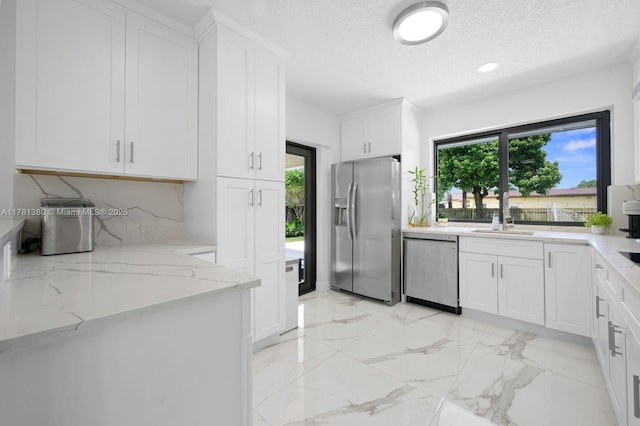 1951 NE 187th Dr, North Miami Beach, FL 33179 - kitchen featuring light stone counters, a wealth of natural light, white cabinets, and stainless steel appliances