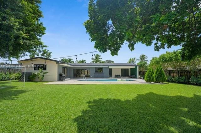 1951 NE 187th Dr, North Miami Beach, FL 33179 - back of property featuring stucco siding, a lawn, a patio, fence, and a fenced in pool