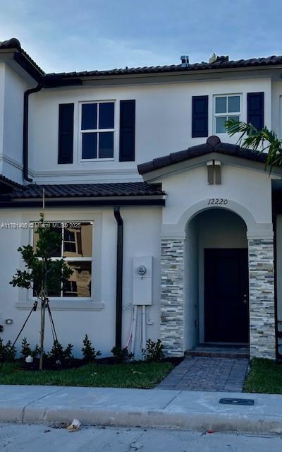 view of front of home featuring a tiled roof, stucco siding, and stone siding