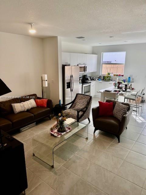 living room featuring light tile patterned floors, visible vents, and a textured ceiling