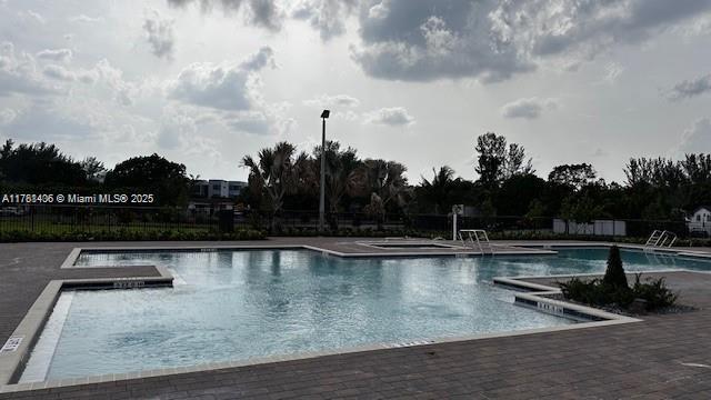 pool with a patio area and fence