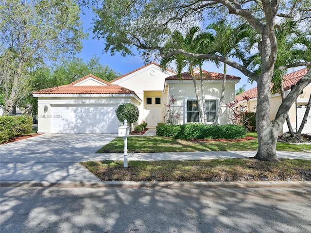 mediterranean / spanish home with a tiled roof, a garage, stucco siding, and concrete driveway