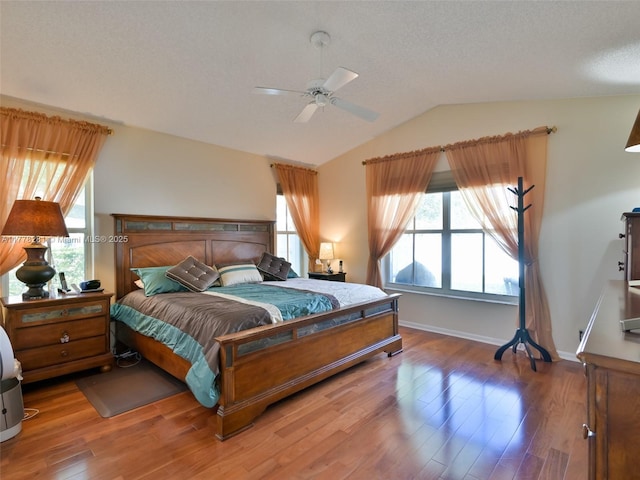 bedroom with baseboards, a ceiling fan, a textured ceiling, wood finished floors, and lofted ceiling