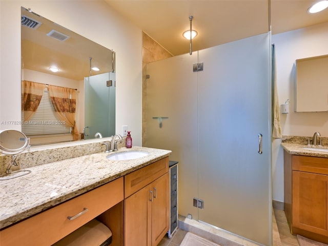 full bath featuring a stall shower, vanity, and visible vents