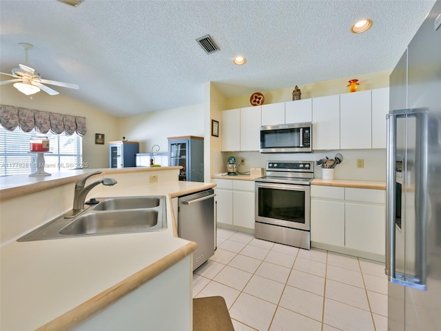 kitchen with light tile patterned floors, a sink, light countertops, vaulted ceiling, and stainless steel appliances