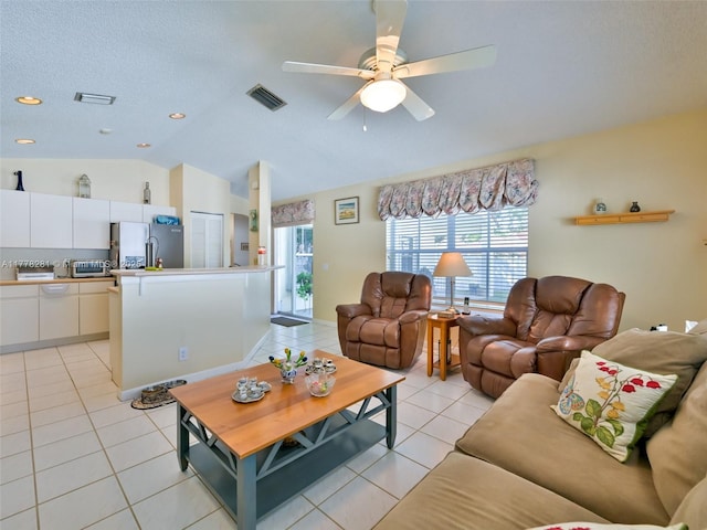 living area featuring a textured ceiling, a ceiling fan, visible vents, light tile patterned flooring, and lofted ceiling