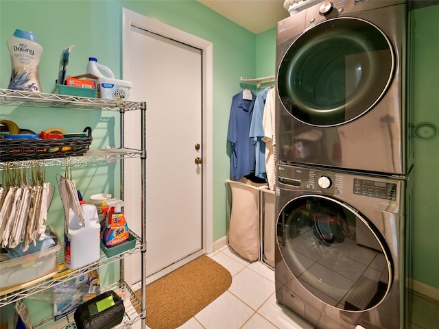 laundry room featuring baseboards, stacked washer / dryer, laundry area, and light tile patterned flooring