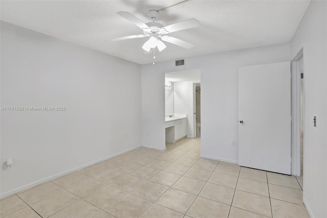 unfurnished bedroom with visible vents, baseboards, light tile patterned floors, and a textured ceiling