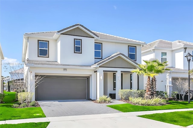 view of front of house with a tiled roof, an attached garage, driveway, and stucco siding