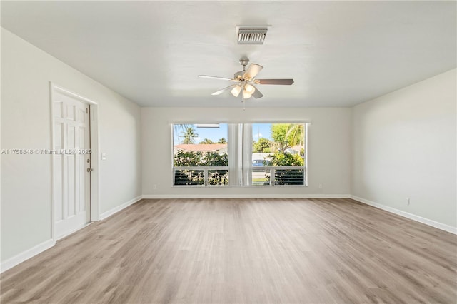 empty room with visible vents, light wood-type flooring, baseboards, and ceiling fan