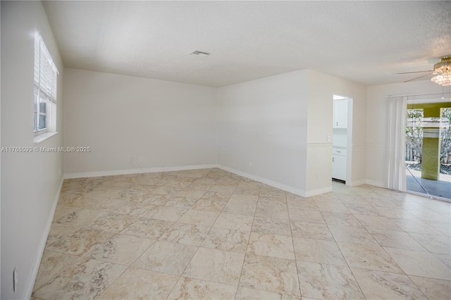empty room with visible vents, baseboards, a ceiling fan, and a textured ceiling
