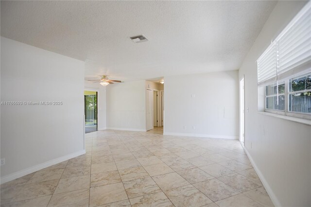 spare room with baseboards, visible vents, a textured ceiling, and a ceiling fan
