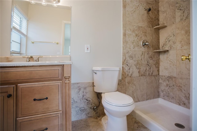 full bath featuring a tile shower, tile walls, vanity, and toilet