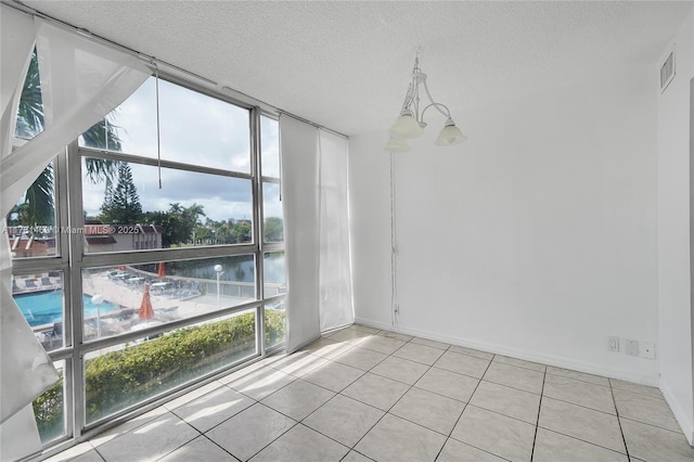 2001 Atlantic Shores Blvd Unit 220, Hallandale Beach, FL 33009 - spare room with visible vents, a notable chandelier, floor to ceiling windows, a textured ceiling, and tile patterned floors