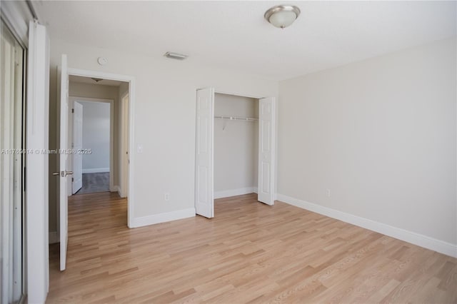 unfurnished bedroom featuring a closet, light wood-style flooring, baseboards, and visible vents