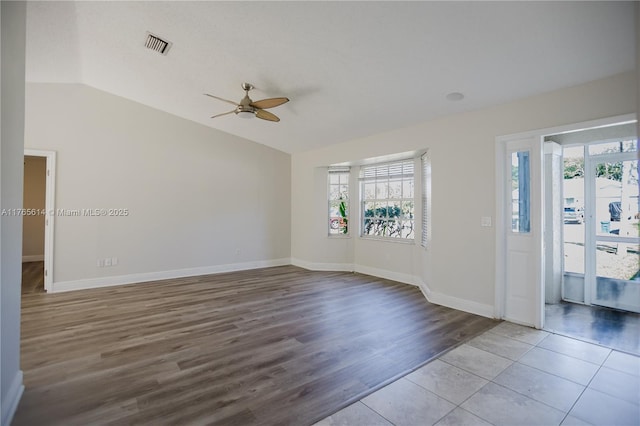 unfurnished room with baseboards, vaulted ceiling, visible vents, ceiling fan, and wood finished floors
