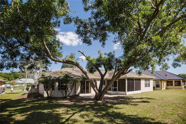 rear view of house with a yard, a sunroom, and stucco siding