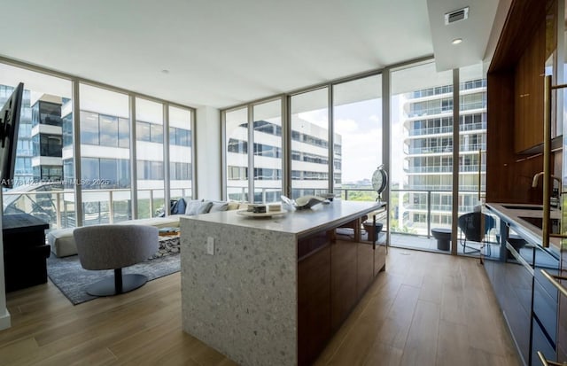 kitchen featuring modern cabinets, wood finished floors, visible vents, and a wall of windows