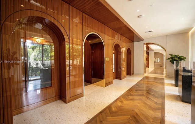 interior space featuring arched walkways, wood walls, visible vents, and baseboards