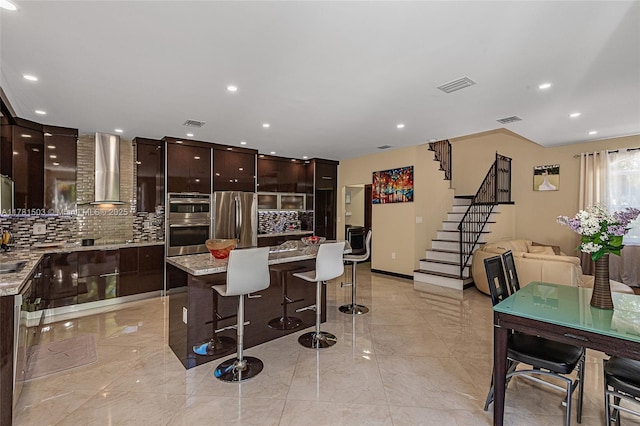 1094 Redwood St ., Unit Hollywood, FL 33019 - kitchen featuring visible vents, wall chimney exhaust hood, modern cabinets, appliances with stainless steel finishes, and a breakfast bar area