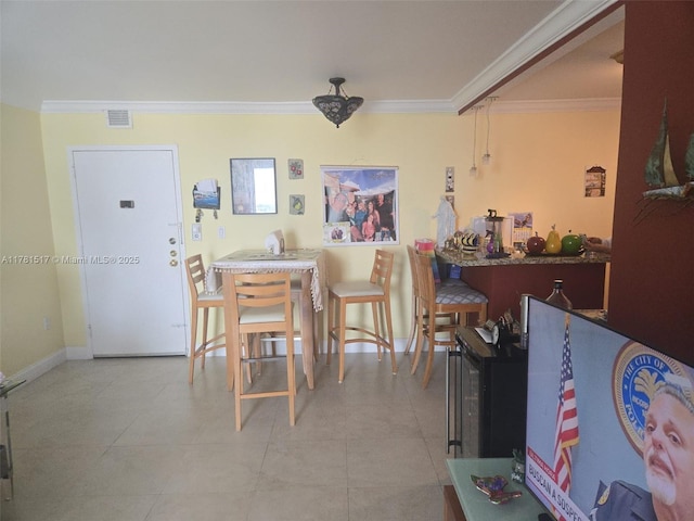 dining space with tile patterned floors, baseboards, ornamental molding, and visible vents