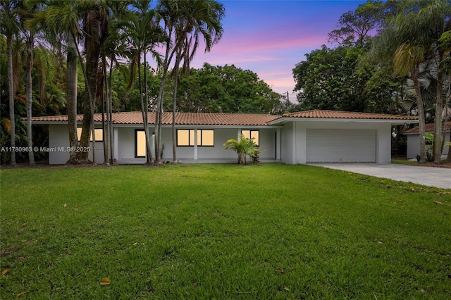 view of front of property featuring a garage, driveway, stucco siding, and a lawn