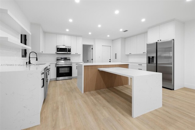 kitchen featuring a sink, a center island, light wood-style flooring, and stainless steel appliances