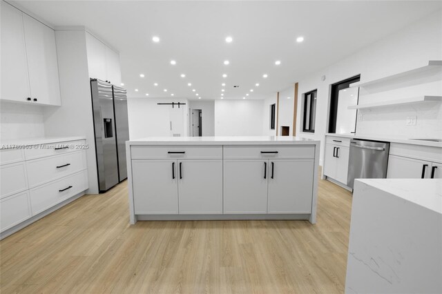kitchen with light wood-style flooring, white cabinetry, recessed lighting, a center island, and stainless steel appliances