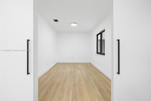 empty room featuring light wood-style flooring, baseboards, and visible vents