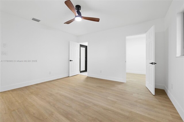 empty room featuring light wood-style floors, visible vents, baseboards, and a ceiling fan