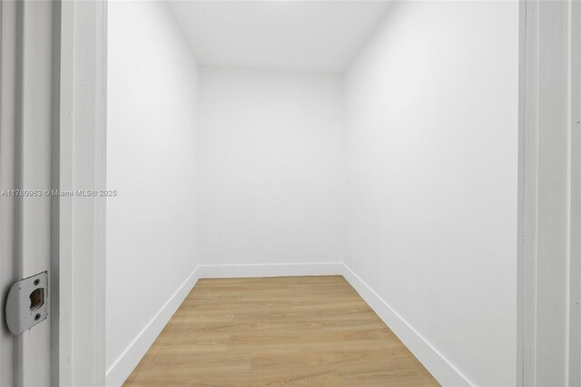 hallway featuring light wood finished floors and baseboards