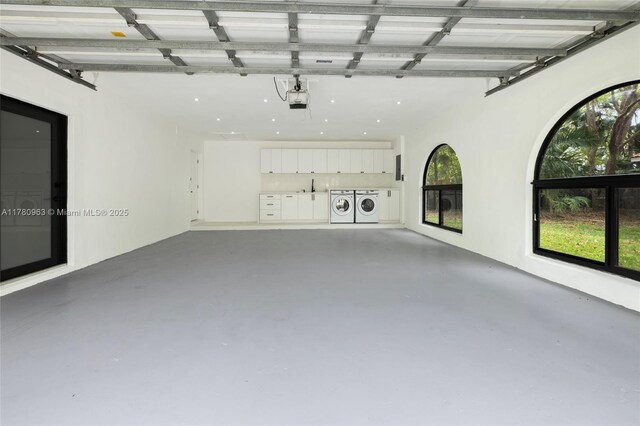 garage featuring a sink, separate washer and dryer, and a garage door opener