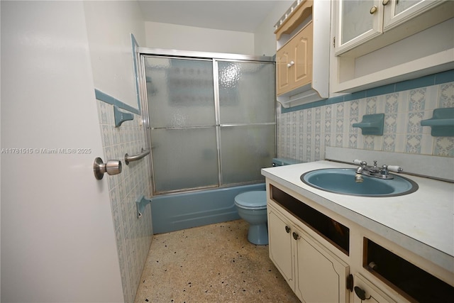 full bath with combined bath / shower with glass door, vanity, backsplash, and toilet
