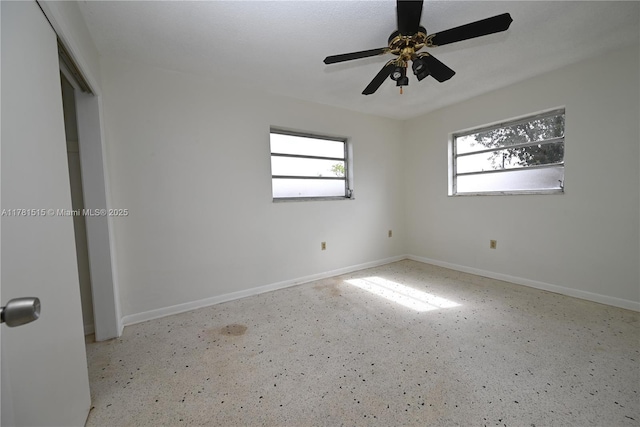 unfurnished room featuring a ceiling fan and baseboards