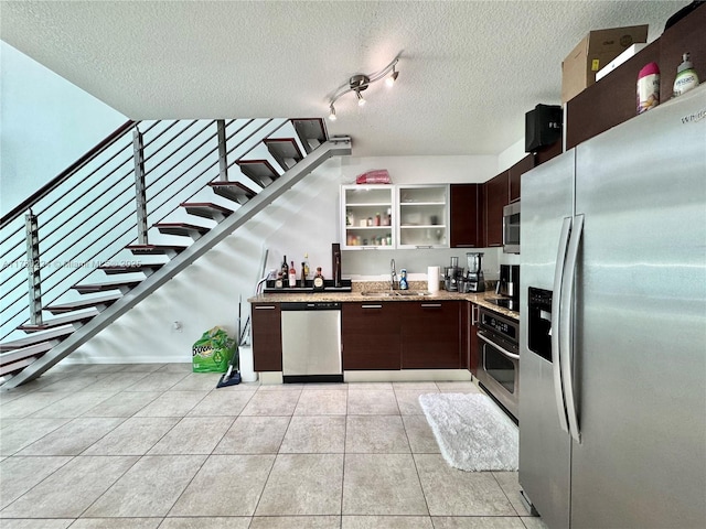kitchen featuring open shelves, a textured ceiling, dark brown cabinets, stainless steel appliances, and light tile patterned flooring