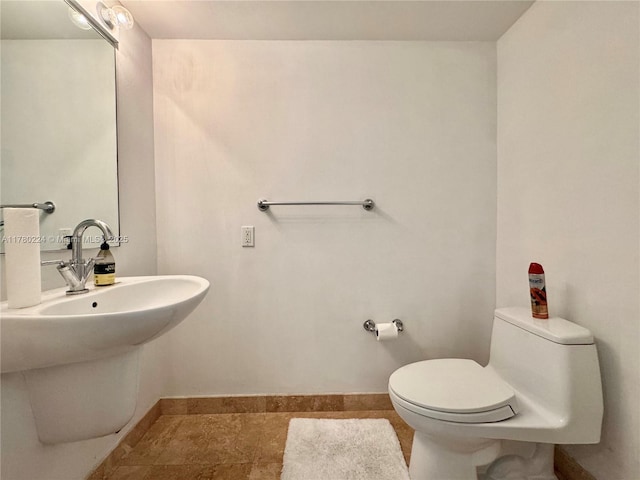 half bathroom featuring a sink, toilet, and baseboards