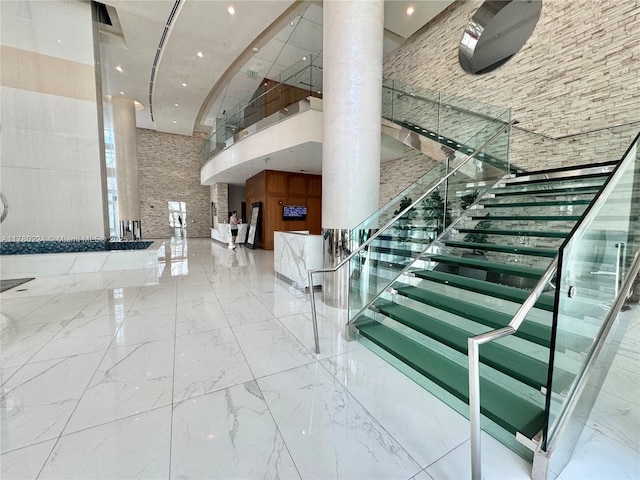 staircase with decorative columns, marble finish floor, a high ceiling, and recessed lighting
