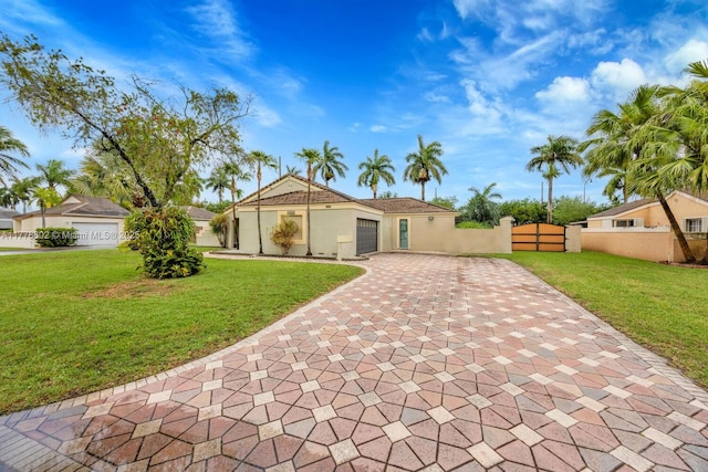 mediterranean / spanish-style house featuring stucco siding, decorative driveway, a front yard, fence, and a garage