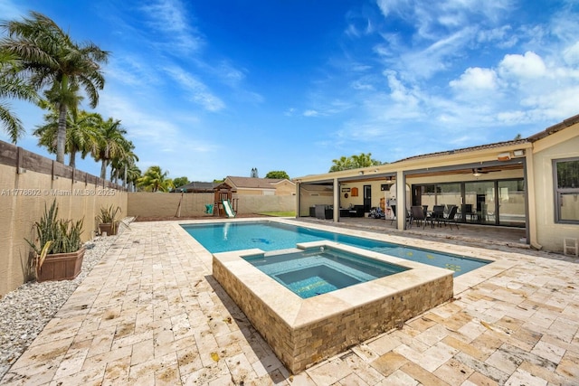 view of pool with a patio, a pool with connected hot tub, a fenced backyard, and a playground