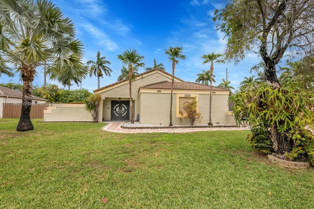 back of property with a yard, a tile roof, fence, and stucco siding