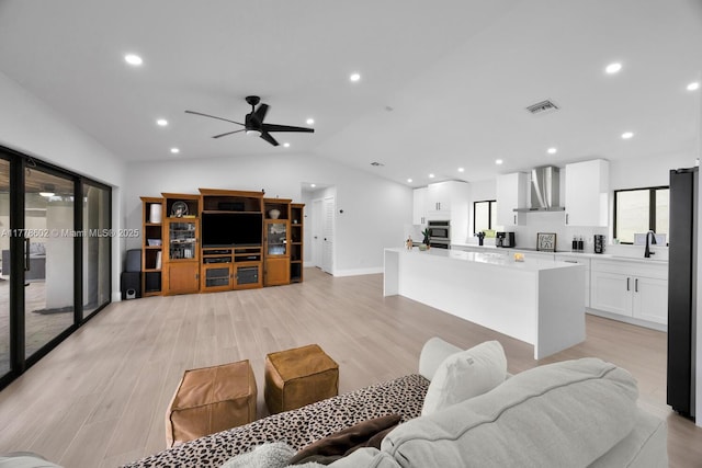 living area with vaulted ceiling, recessed lighting, light wood-style flooring, a ceiling fan, and visible vents
